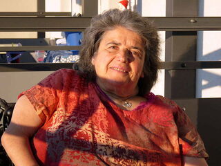 Foto: Marita in rot-orange-farbenenr Bluse im Potrait in Halbdistanz auf meinem Balkon.