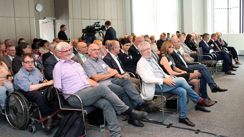 Foto: Das Publikum im vollbesetztebn Saal links und rechts des Mittelganges.