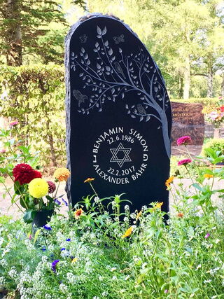 Foto: Benjamin's Grabstein mit seinen Namen in Kreisform und einem blätterreichen Ast eines Baumes darauf.