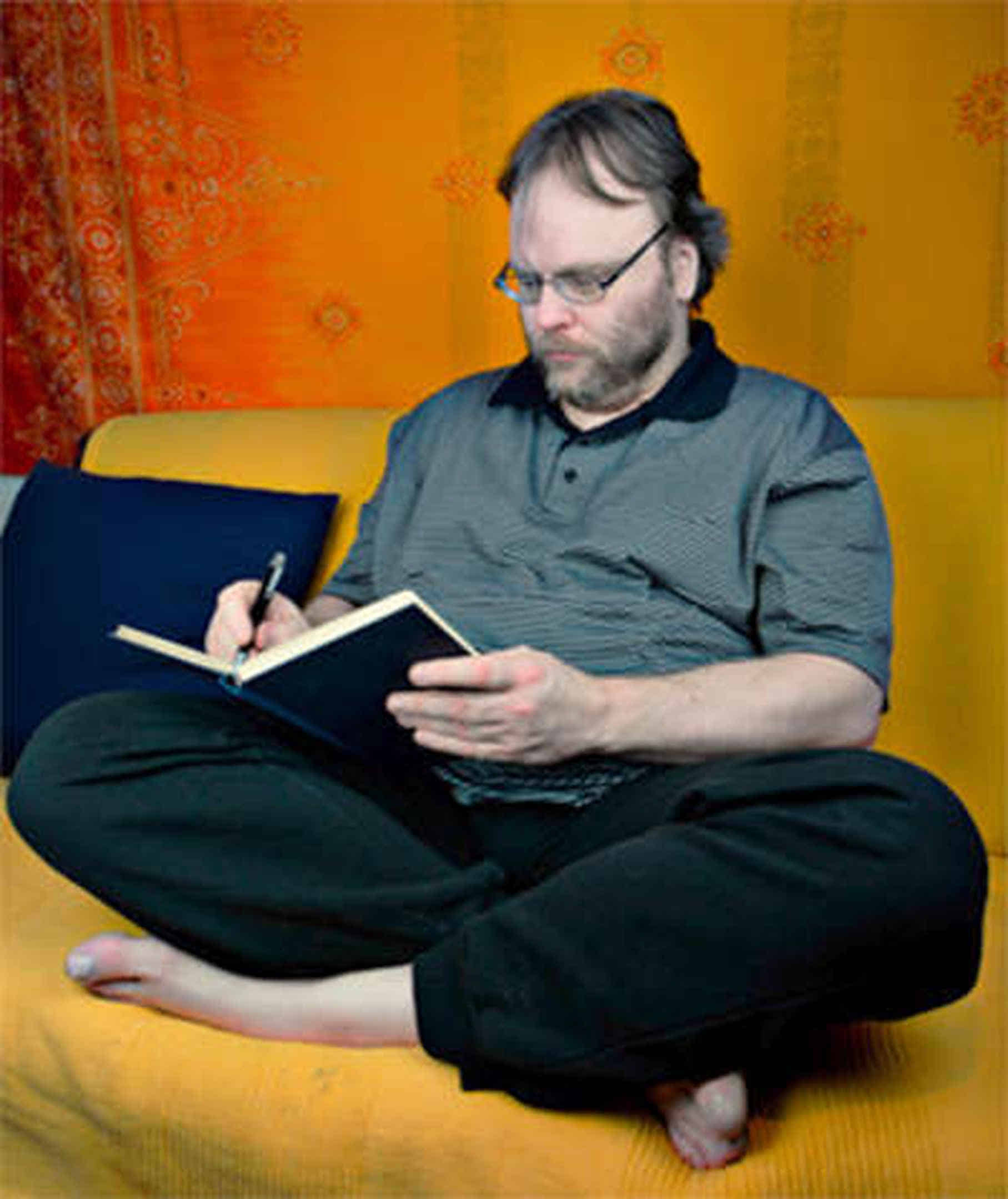 Foto: Ich sitze in meinem Snoozleraum auf dem Sofa und schreibe einen Text in mein Schreibbuch.